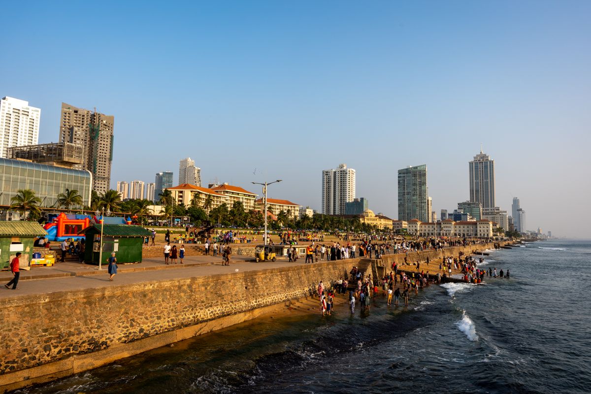 Crowds along Galle Face Green's oceanfront promenade with Galle Face Hotel and Colombo's skyline beyond
