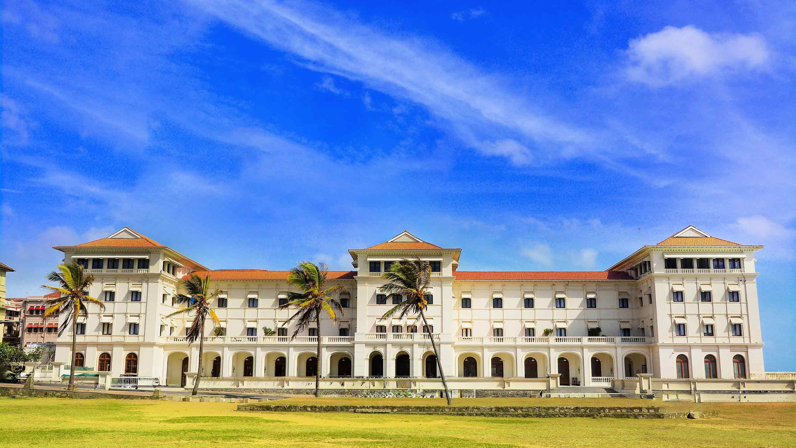 Front facade of Galle Face Hotel beneath a vivid blue sky